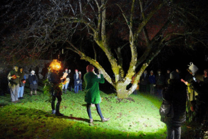 Group of people singing around a tree at dusk