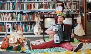 Photo of performer sat on floor playing an accordion